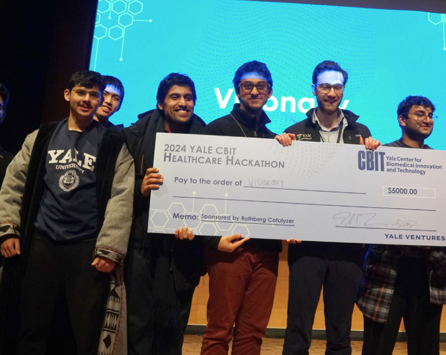 Students with a big check at the hackathon